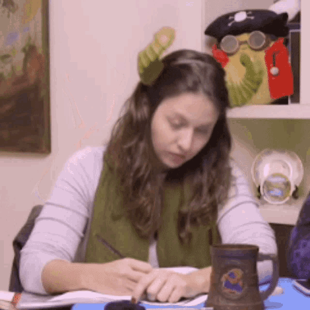 a woman sitting at a desk with a pirate hat on