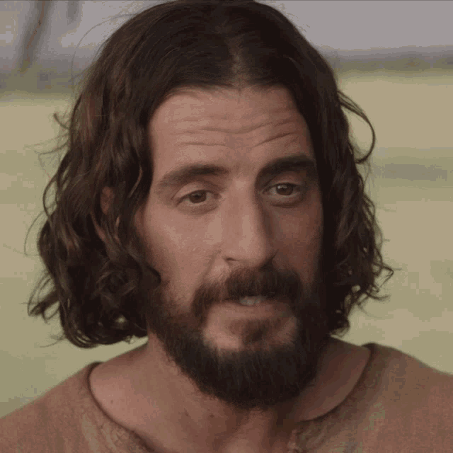 a man with long hair and a beard looks to the side