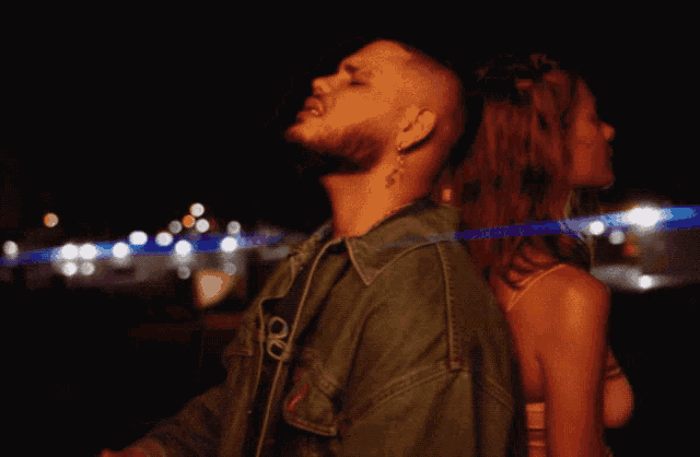 a man and a woman are standing next to each other and the man has a tattoo on his ear
