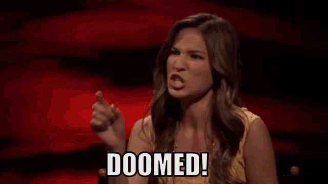 a woman is sitting in a chair and pointing at the camera while saying `` doomed ! ''