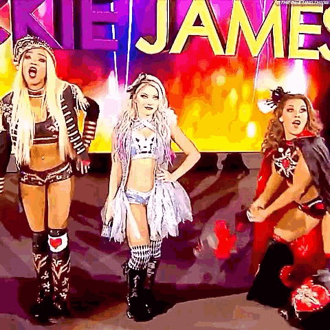 three female wrestlers are standing in front of a sign that says james .