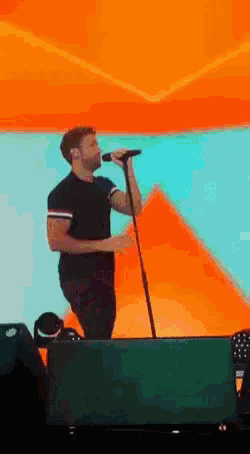 a man singing into a microphone while standing on a stage