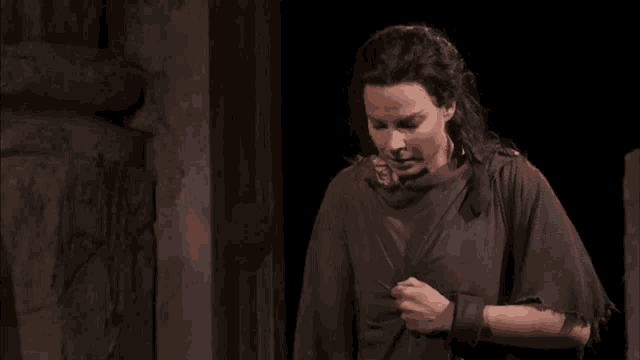 a woman in a brown poncho is holding a sword
