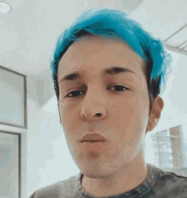 a young man with blue hair is making a face