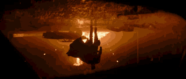 a silhouette of a person falling into a fire