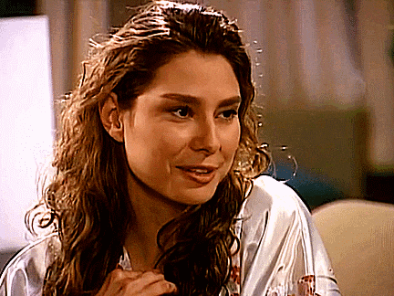a woman with curly hair is wearing a white robe and smiling