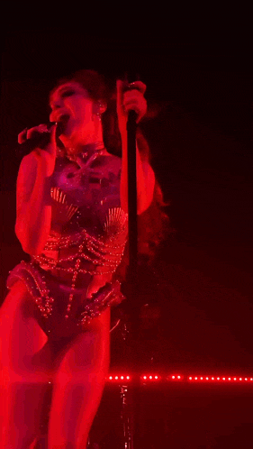 a woman is singing into a microphone with a tattoo on her arm that says ' i love you '