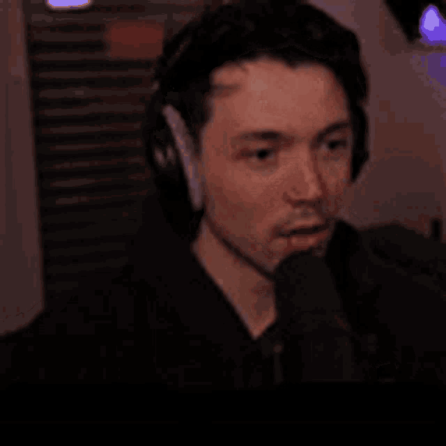 a man wearing headphones and a microphone is talking into a microphone .