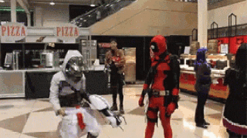 a man in a deadpool costume is standing in front of a pizza sign