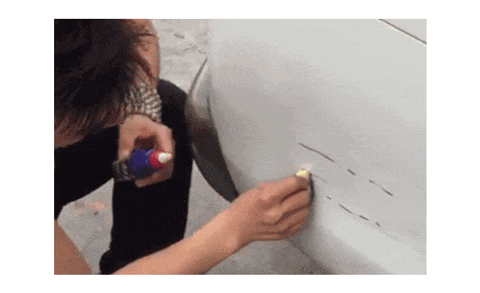 a woman is scratching a car with a marker and a sponge .