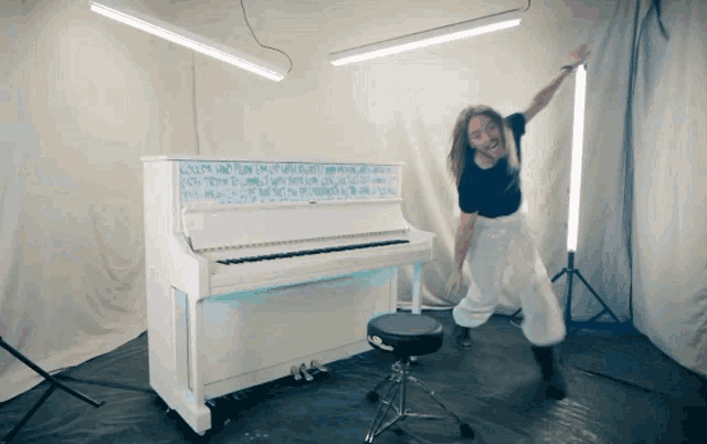 a woman is dancing in front of a white piano that has the word love on it