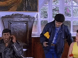 a man in a leather jacket is talking on a cell phone while a woman in a yellow dress holds a red rose .