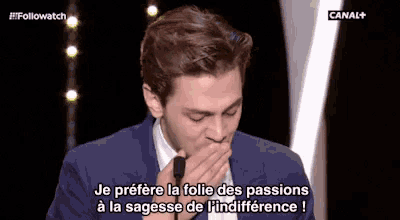a man in a suit is covering his mouth while talking into a microphone .