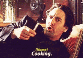 a man is laying on a couch with a book in his hand and says home cooking