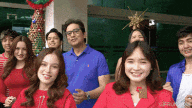 a group of people standing in front of a christmas tree with gifrun.com written on the bottom right