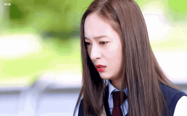 a woman with long hair and red lipstick is wearing a school uniform .