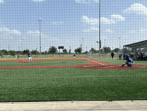 a baseball game is being played on a field with a scoreboard behind the fence that shows the score as a tie