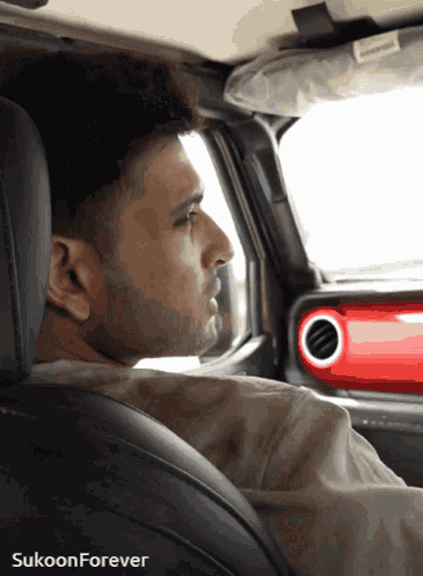 a man is sitting in the back seat of a car with sukoon forever written on the bottom