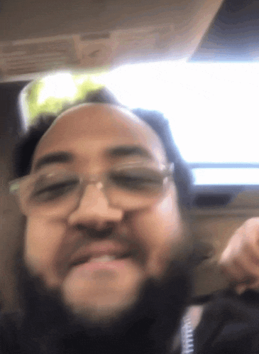 a man with glasses and a beard is smiling for the camera