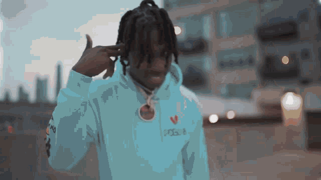 a young man in a blue hoodie is making a peace sign with his hands