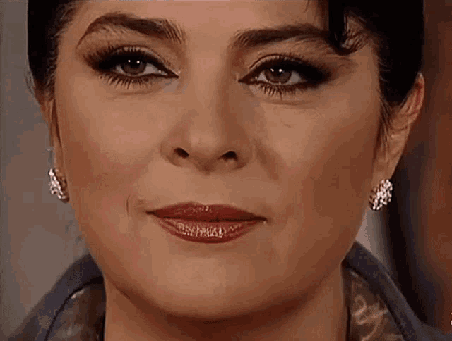 a close up of a woman 's face with earrings and red lipstick