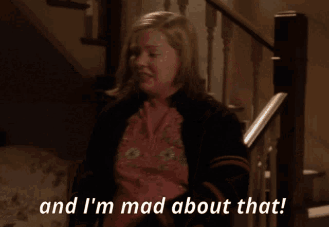a woman says " and i 'm mad about that " in front of a staircase