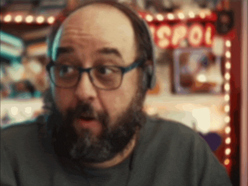 a man with a beard wearing headphones stands in front of a sign that says spool