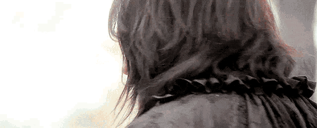 a close up of a woman 's back with long hair and a black jacket .