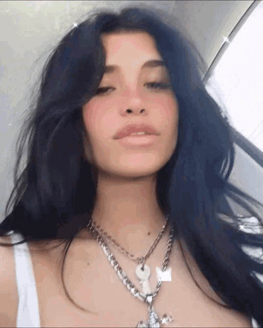 a woman wearing a white tank top and a silver necklace