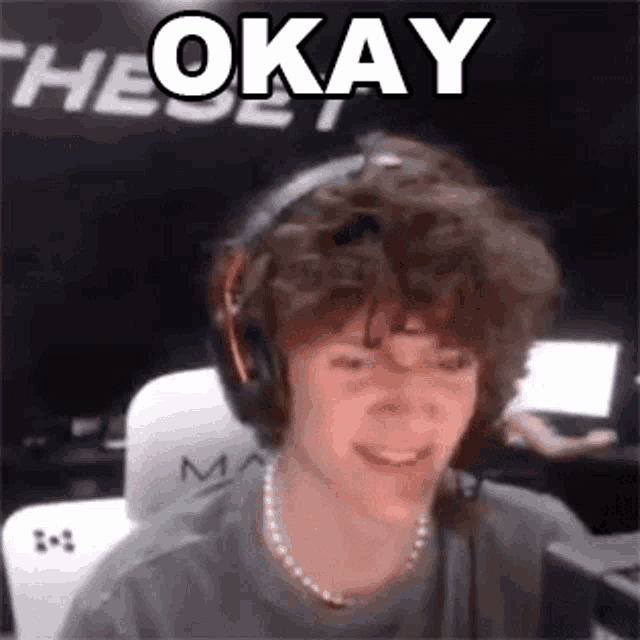 a young man with curly hair is wearing headphones and a necklace and smiling .