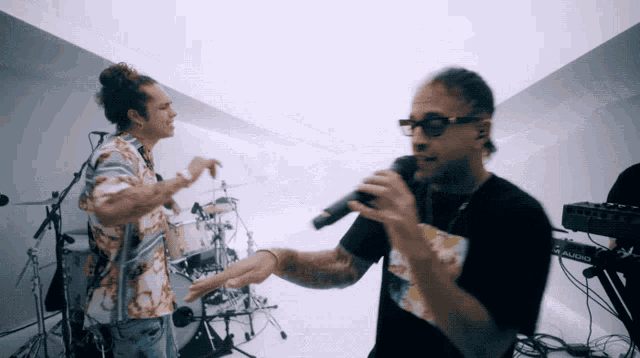 a man singing into a microphone while another man stands behind him