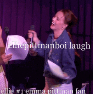 ellie pittman boi laughs while holding a piece of paper in front of a microphone