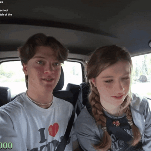 a boy and a girl are sitting in the back seat of a car and the girl has a shirt that says i love ny