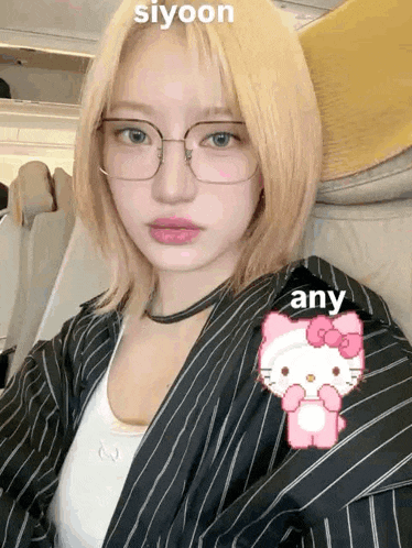 a girl wearing glasses and a hello kitty sticker on her jacket .