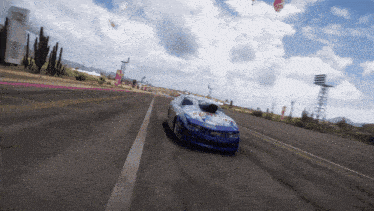 a blue and white race car is driving down a desert highway