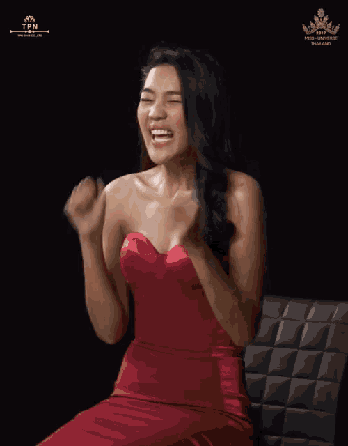 a woman in a red dress is sitting in front of a black background that says thailand on it