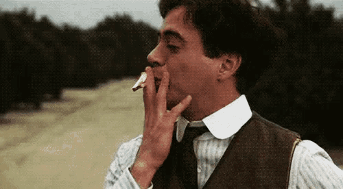 a man in a vest and tie is eating a piece of bread .