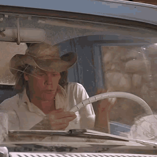 a man wearing a cowboy hat is sitting in a car