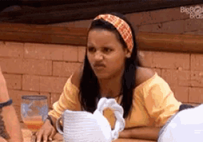 a woman wearing a headband and a yellow shirt is sitting at a table with a pitcher .