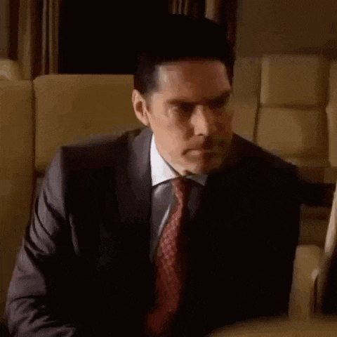 a man in a suit and tie is sitting in a chair and looking at something .