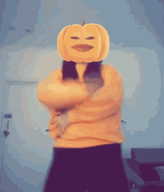 a woman with a pumpkin on her head is wearing an orange sweater