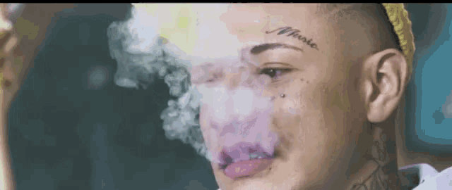 a close up of a man smoking a cigarette with smoke coming out of his mouth .
