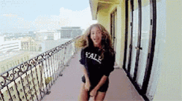 a woman wearing a yale shirt is dancing on a balcony .