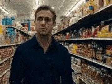 a man in a blue shirt is standing in a grocery store .