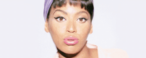 a woman wearing a purple headband and pink lipstick looks at the camera