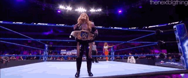a woman in a wrestling ring is holding a wrestling championship belt
