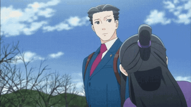 a man in a suit and tie stands next to a woman in a purple dress