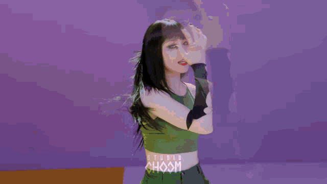 a woman wearing a green tank top with the word choom on it is smiling .
