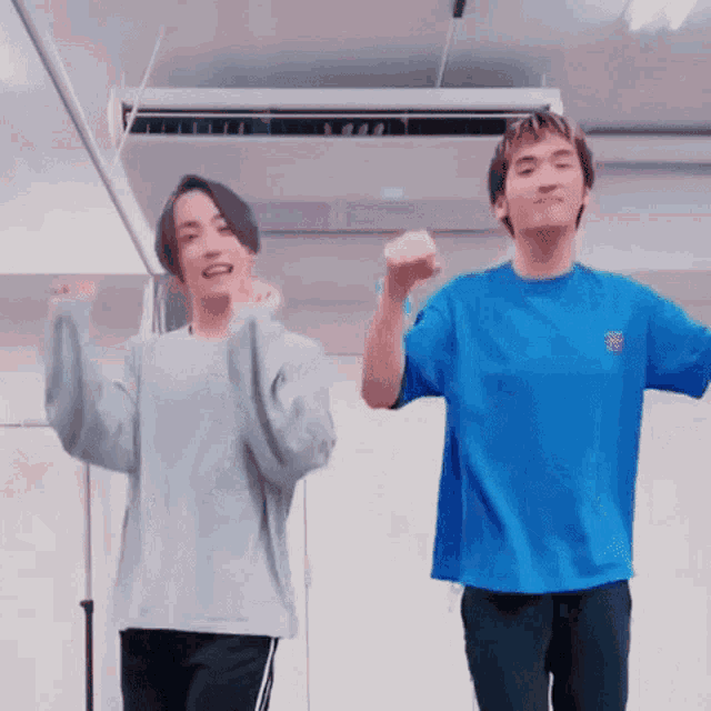 two men are dancing together in a room with their hands in the air .
