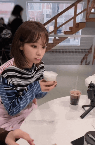 a girl sitting at a table with a cup of coffee